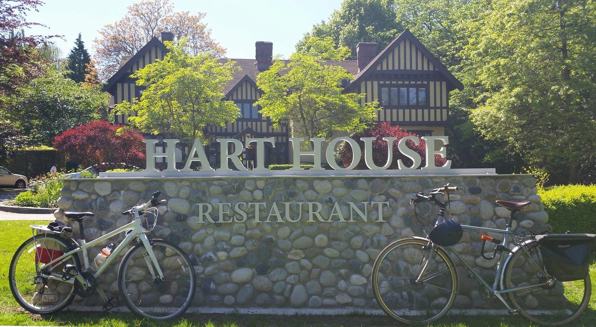 Bicycles parked in front of Hart House Restaurant sign with Tudor-style building and gardens in Burnaby