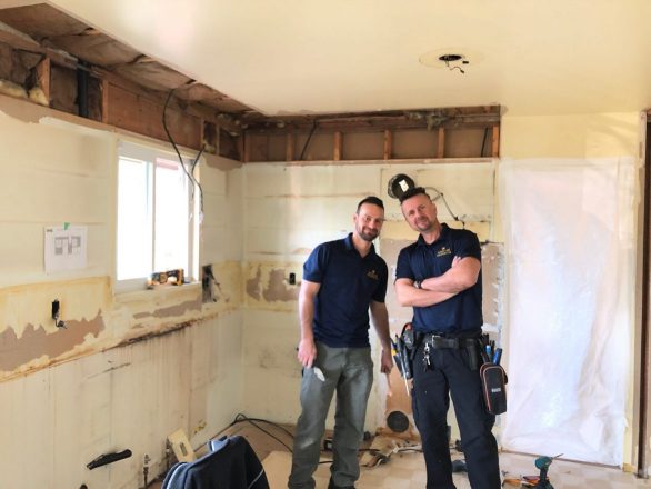 Two electricians in blue shirts posing in a kitchen renovation in Burnaby during an electrical installation project