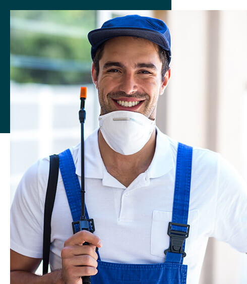 Smiling male pest control worker in blue uniform and cap holding spraying equipment