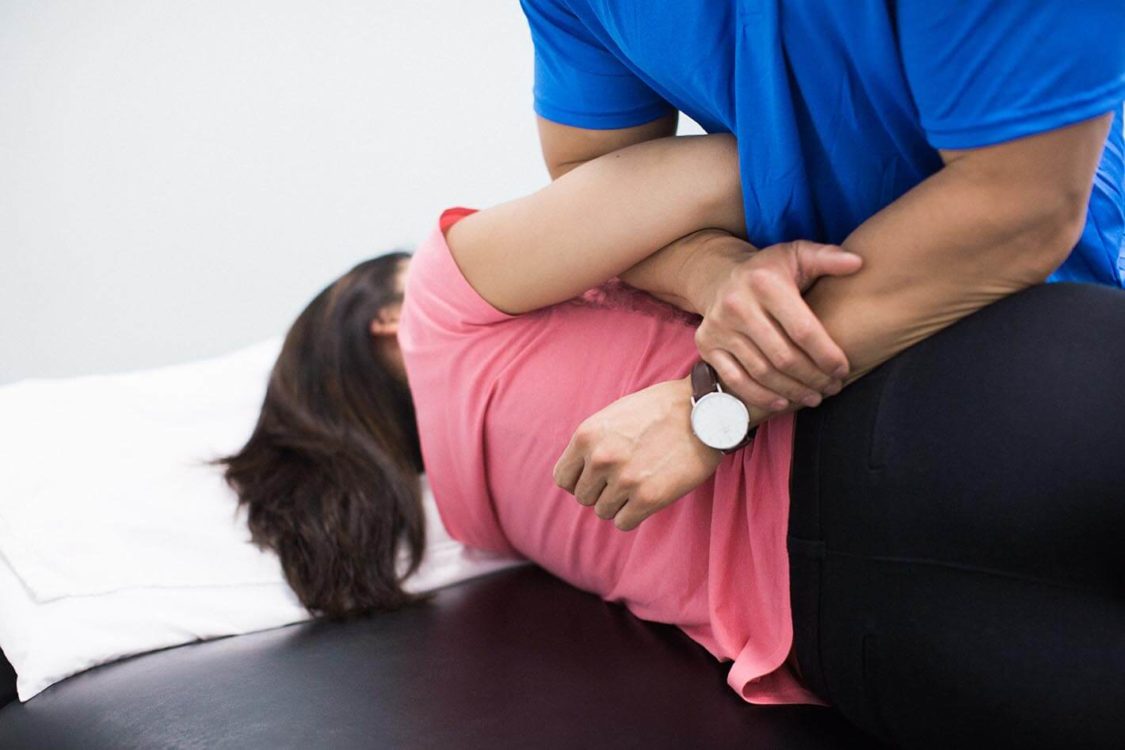 Physiotherapist performing knee examination on patient during home physiotherapy session in Burnaby
