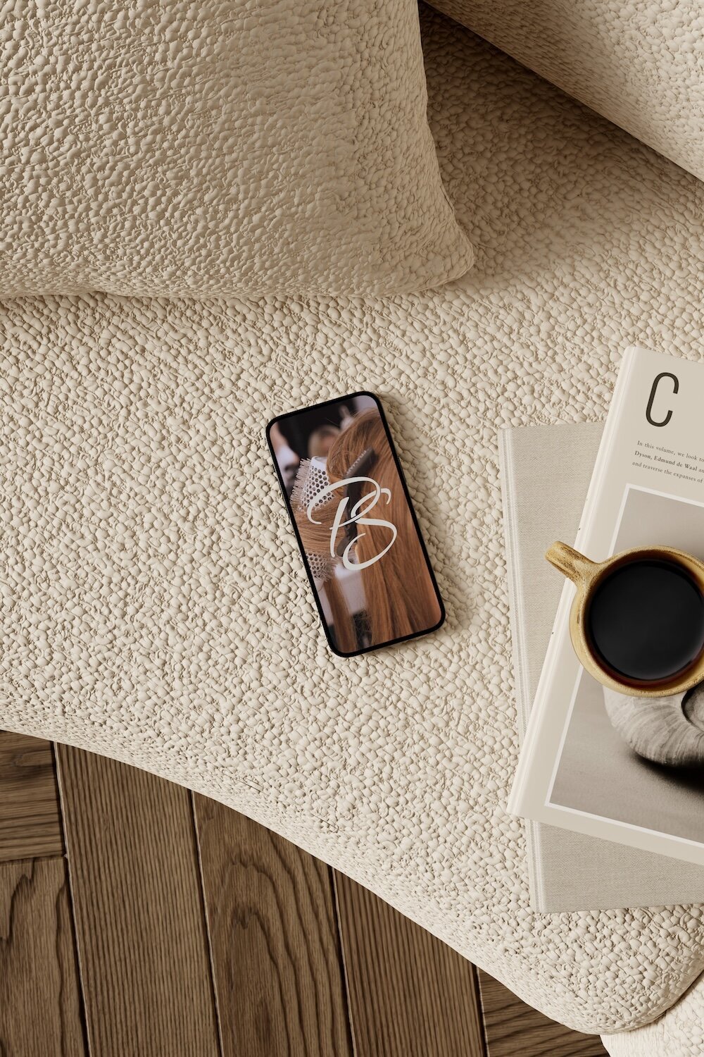 Flat lay product mockup showing a smartphone displaying elegant salon branding on a cream textured rug with a coffee cup and magazine in a modern spa setting