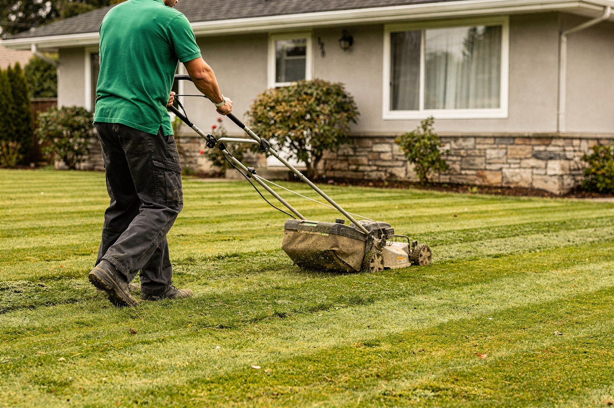 Lawn care professional mowing a neat residential yard in Burnaby