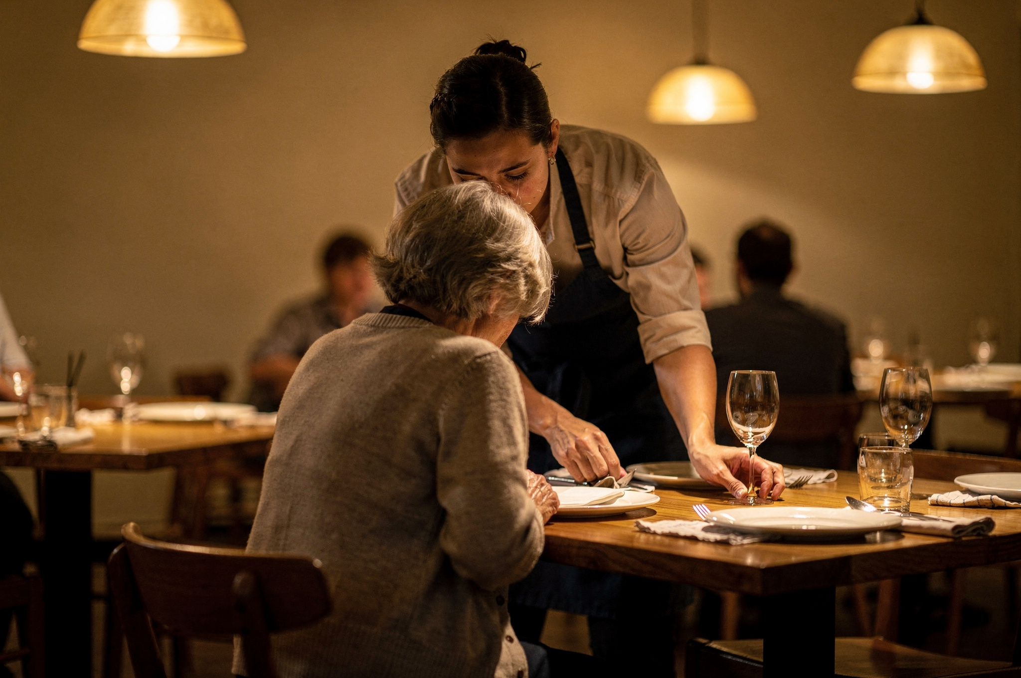Restaurant server assisting a senior diner at her table