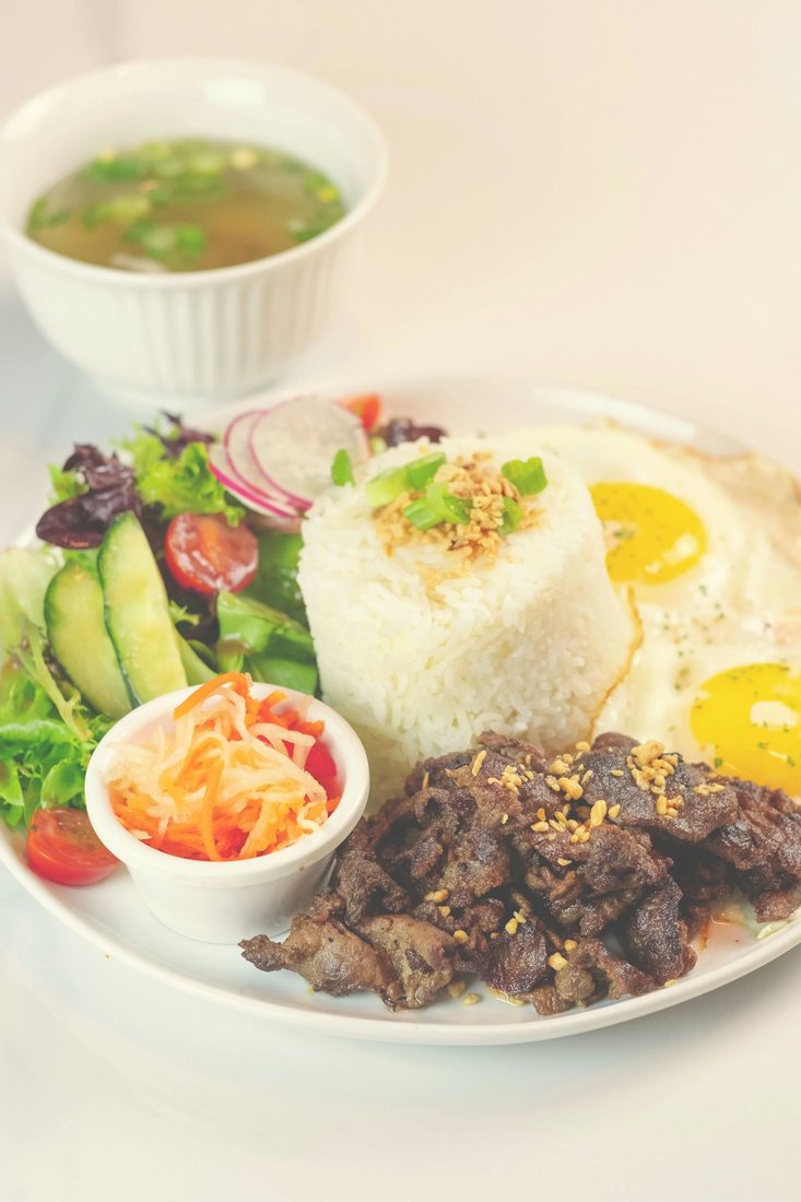 A silog brunch plate at Halina with two fried eggs, garlic rice, atchara, salad and a cup of soup